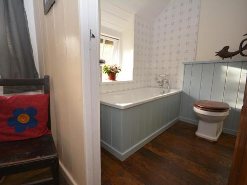 a bathroom with a tub and a toilet and a window at 3 Bed in Aberaeron 55308 in Ciliau-Aeron