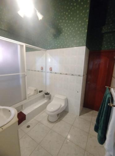 y baño con aseo, bañera y lavamanos. en Posada de Zory, en Santo Domingo de los Colorados