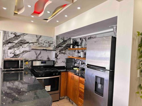 a kitchen with a stainless steel refrigerator and wooden cabinets at Villa Marbella by Potenza Rentals in Santo Domingo
