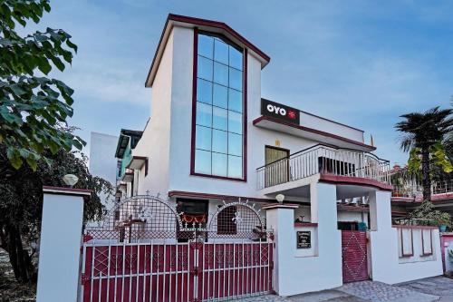 un edificio con una valla roja delante de él en OYO Home Picturesque Stay en Dehradun