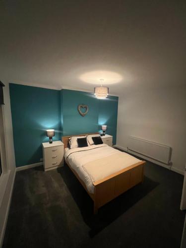 a bedroom with a bed and a blue wall at Cosy home perfect for families and contractors with free parking in Darlington