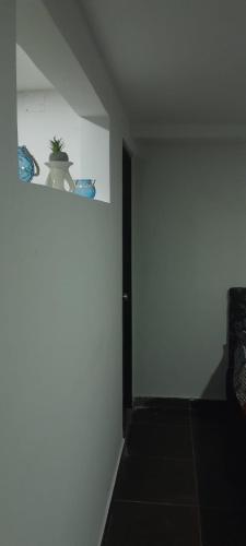 a room with a white wall with a plant on a shelf at El Encanto III - ApartaSuite in Barranquilla