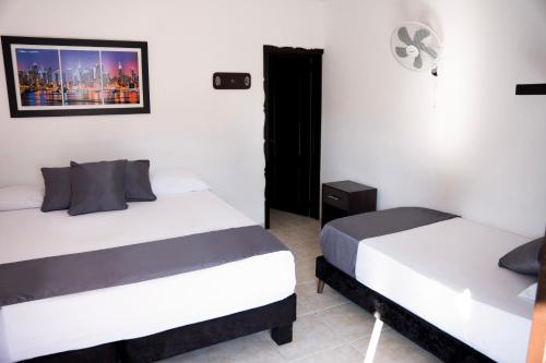 two beds in a room with white walls at Finca Hotel Palmas Del Edén in Armenia