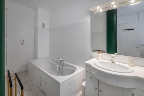 a white bathroom with a tub and a sink at The Sunrise, Spacious, fully equipped, 2 parkings, 8p, tramway 1,2,4 in Montpellier