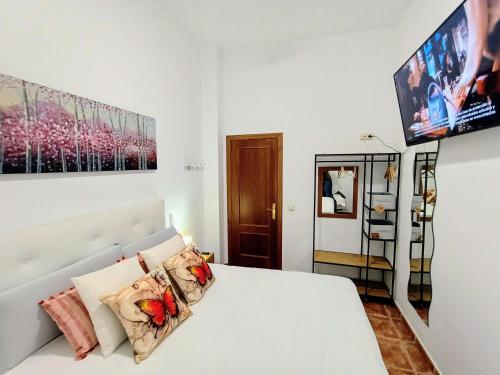 1 dormitorio con 1 cama blanca y TV en Casa Rural Agua de Azahar Chimenea, en Zahara de la Sierra