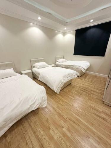 Zimmer mit 3 Betten und einem großen Bildschirm in der Unterkunft شقة جميلة بغرفتين نوم ودخول ذاتي 106B in Riad