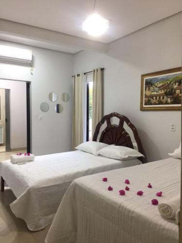 two beds in a bedroom with roses on the sheets at HOSTEL D´ SALLES (PRÓXIMO AO AEROPORTO) in Palmas