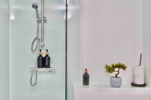 a shower with bottles and a plant on a shelf at Next to Headingley Stadium - Perfect for Families & Work - Contact us for Better Offers! in Headingley