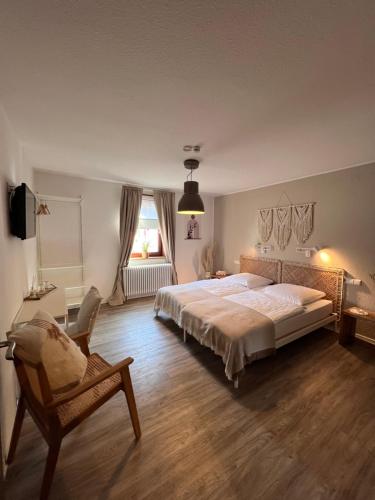 a bedroom with a large bed and a chair at Pension Krone Sternenfels in Sternenfels
