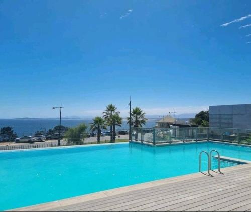 a large blue swimming pool with a view of the ocean at Frente a la playa. Vista al mar. in Concón