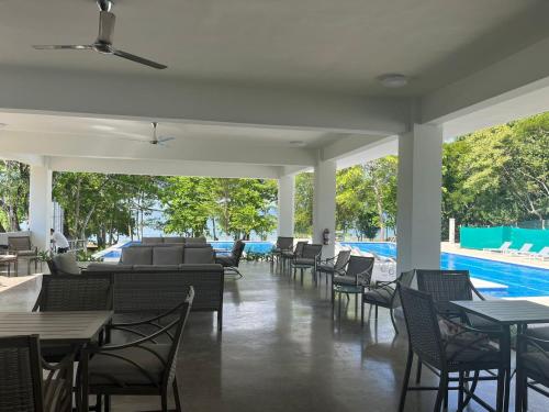 a restaurant with tables and chairs and a pool at Punta Esmeralda by Punta Leona in Jacó