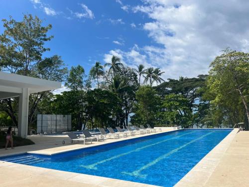 蓬塔雷納斯的住宿－Punta Esmeralda by Punta Leona，一个带椅子和树木的大型游泳池