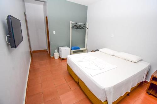 a bedroom with a bed and a tv on a wall at Pousada das Aguas in Caldas Novas