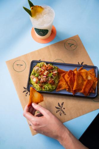 a person holding a plate of food with chips and dip at Plaza San Antonio Hotel & Spa, Autograph Collection in San Antonio