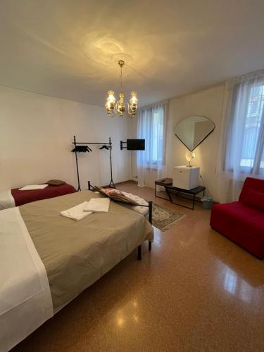 een slaapkamer met een bed en een rode stoel bij Lions Venice Guest house in Venetië