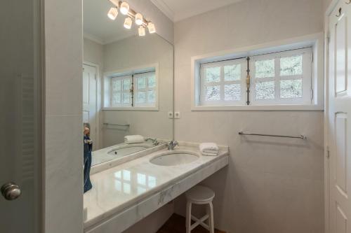 a white bathroom with a sink and a mirror at Quinta das Casas - Douro Winery & Villas in Vila Real