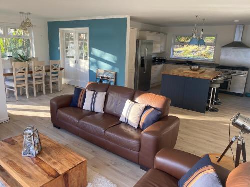 a living room with a brown couch and a kitchen at the waterside - carrick castle - loch goil in Carrick