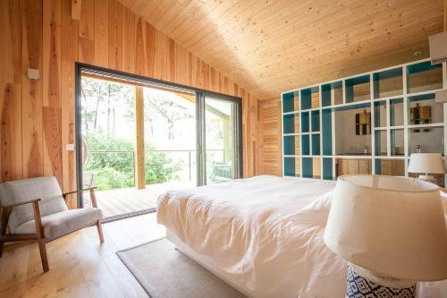 ein Schlafzimmer mit einem großen Bett und einem großen Fenster in der Unterkunft Villa Des Sittelles - Cap Ferret in Lège-Cap-Ferret