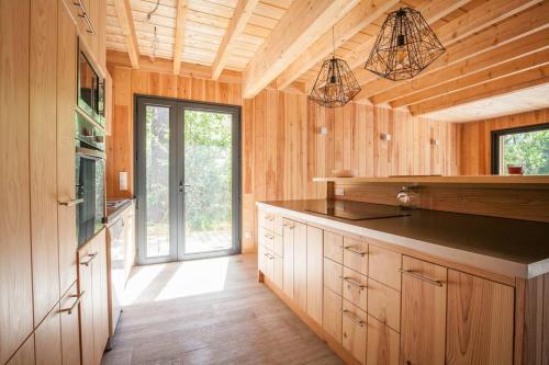 una cocina con armarios de madera y una encimera grande en Villa Des Sittelles - Cap Ferret, en Lège-Cap-Ferret