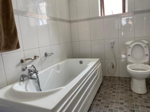 a white bathroom with a tub and a toilet at Missions Cafe Arua - GuestHouse in Arua