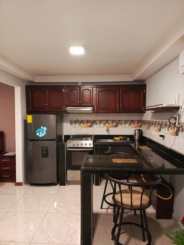 uma cozinha com armários de madeira e um balcão preto em Mimo'Suits & rooms em Machala