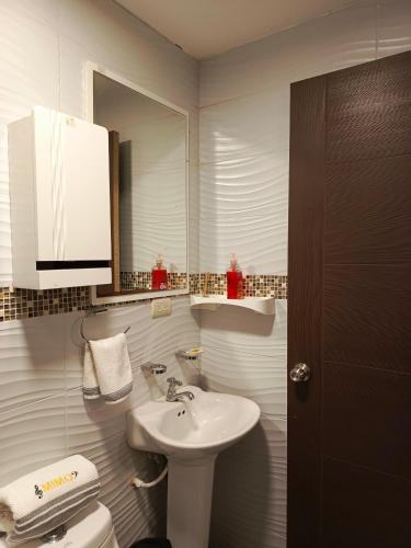 Baño blanco con lavabo y aseo en Mimo'Suits & rooms, en Machala