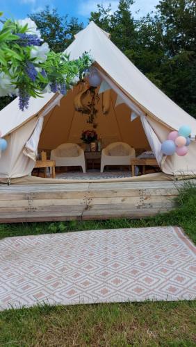 Hopgarden Glamping Exclusive site hire - Sleep up to 50 guests في Wadhurst: خيمة مع كراسي وطاولة في العشب