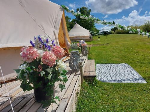 Hopgarden Glamping Exclusive site hire - Sleep up to 50 guests في Wadhurst: خيمة مع حفنة من الزهور على سطح السفينة