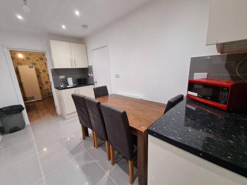 uma cozinha com uma mesa de madeira e bancada preta em Cheerful 4/5 bed house - Heathrow em West Drayton