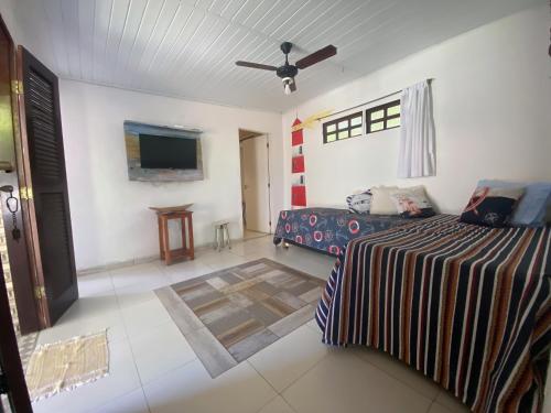 - une chambre avec un lit et une télévision à écran plat dans l'établissement Golfinho Condomínio, à Arraial d'Ajuda