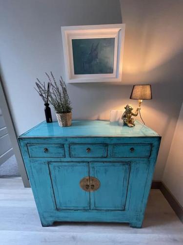 a blue dresser with a lamp on top of it at Spanish Point Luxury Home beside sea with Sauna! in Droíchead an Chláir