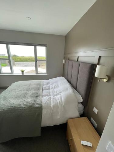 a bedroom with a large bed and a window at Spanish Point Luxury Home beside sea with Sauna! in Droíchead an Chláir