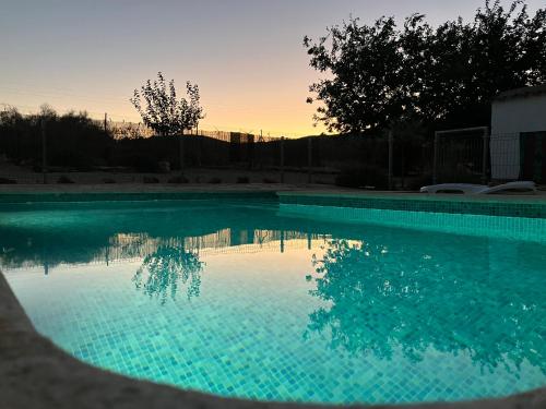 einen Pool mit Sonnenuntergang im Hintergrund in der Unterkunft La Huerta el Bao in Alhambra