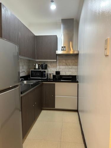 eine Küche mit einem Kühlschrank und einem Herd Top-Backofen in der Unterkunft Gramercy Residences 46th Floor 1 Bedroom Sunset View in Manila
