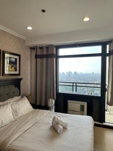 Gramercy Residences 46th Floor 1 Bedroom Sunset View في مانيلا: سرير عليه حشره محشوره امام النافذه