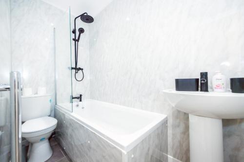 a white bathroom with a toilet and a sink at Benoît Apartments in Manchester