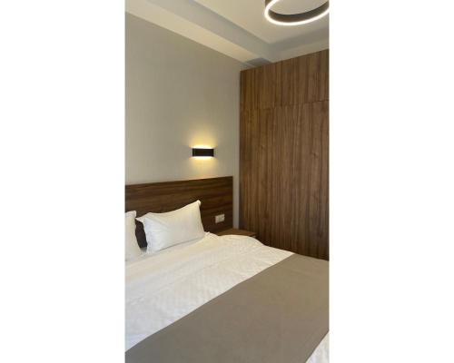 Schlafzimmer mit einem weißen Bett mit einem Kopfteil aus Holz in der Unterkunft Crystal Loft Bakuriani - A406 in Bakuriani