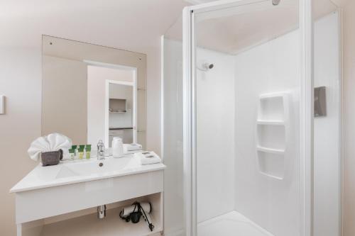 a white bathroom with a sink and a shower at Avalon Motel Thames - Wenzel Motels in Thames