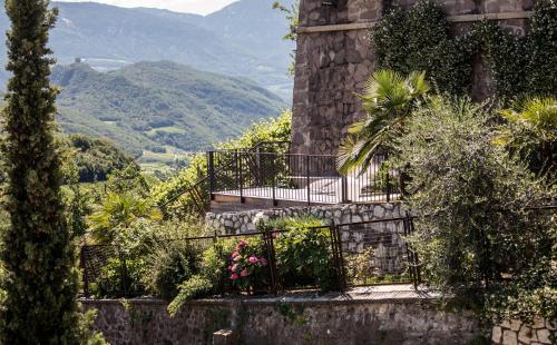 a stone building with a balcony with plants and flowers at Romantik Hotel Jagdhof in Caldaro