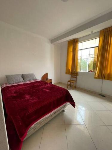 a bedroom with a large bed with a red blanket at Yachanapaq Wasi III in Huanta