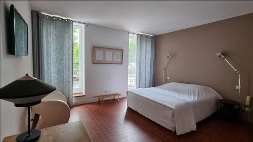 a bedroom with a bed and a large window at Hotel Burrhus in Vaison-la-Romaine