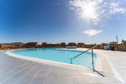 a large swimming pool with the sun in the sky at Villa Colibri Azul in Lajares