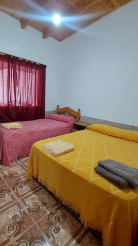 a bedroom with two beds with yellow sheets and red curtains at MALARGÜE in Malargüe