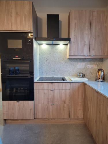 a kitchen with wooden cabinets and a stove top oven at Maisie and Bea's cottage in Galway