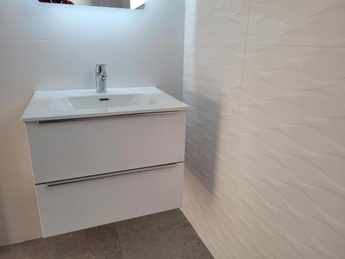 a white bathroom with a sink and a wall at Maisie and Bea's cottage in Galway