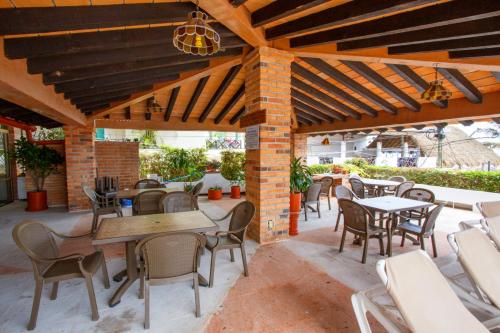 an outdoor patio with tables and chairs and a brick wall at Playa Bonita unit Beso del Sol 101 in Puerto Vallarta