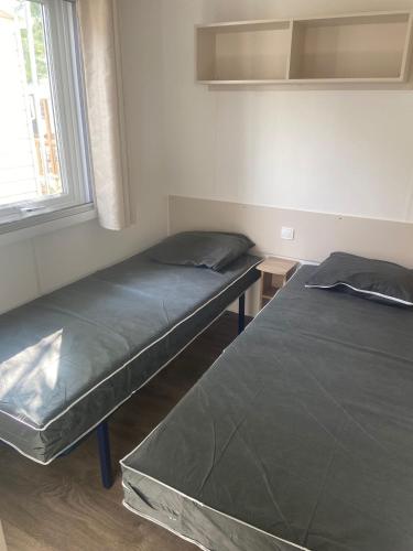 two beds sitting in a room with a window at Mobilhome 4/6 personnes in Valras-Plage