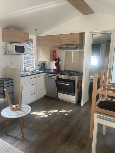 a kitchen with white cabinets and a stove top oven at Mobilhome 4/6 personnes in Valras-Plage