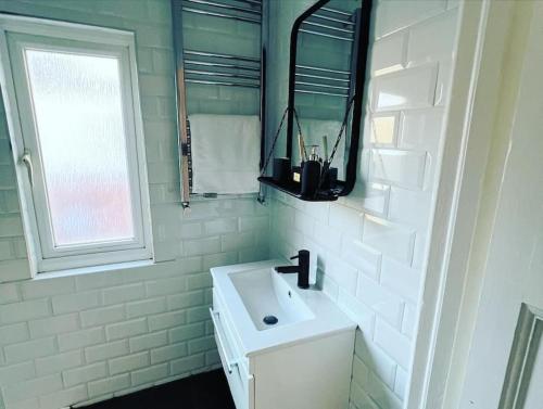 a white bathroom with a sink and a window at Hill Grove 2 Bedroom Apartment in Southend-on-Sea