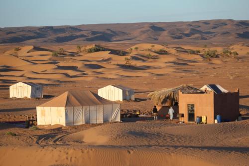 a desert camp in the desert with sand dunes in the background at Majorelle Desert Camp in Zagora